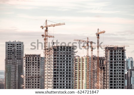 Building crane and buildings under construction against evening sky