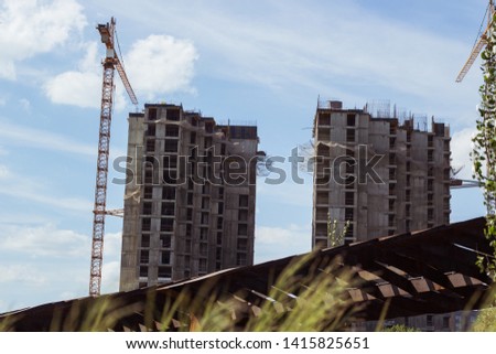 building cranes at front of a multi-storey uilding under construction, new house for many families, building.