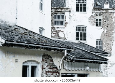 The building displays a mix of old architecture and decay, with peeling paint, broken windows, and a weathered roof. This site evokes a sense of history and abandonment. - Powered by Shutterstock