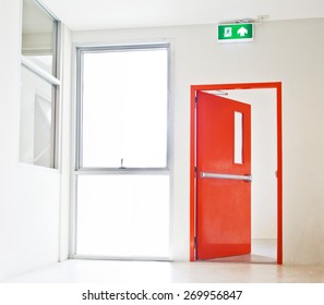 Building Emergency Exit With Exit Sign, Red Door Opening To White