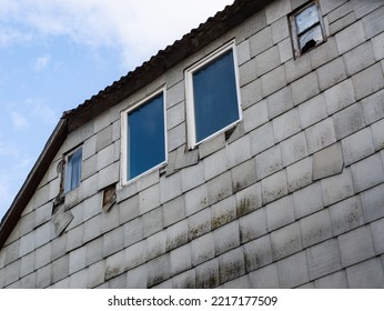 Building Facade With Asbestos Sheets. Damaged Exterior Of An Old House. The Grey Plates Are Fibrous Material That Is Toxic For People And The Nature. The Removal Of Asbestos Is Very Expensive.