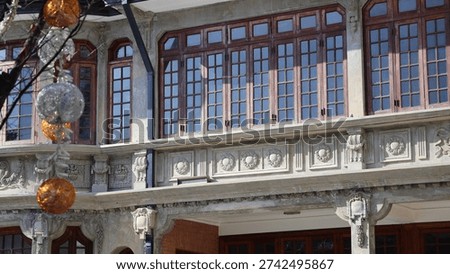A building facade with classical architectural features. The structure prominently showcases an intricate balcony with carved details and arched openings