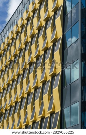 Building facade featuring repeating yellow geometric patterns and reflective glass windows