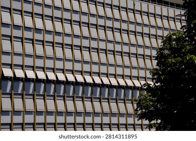 Building facade with repetitive patterns of opened and closed sun blinds creating light and shade