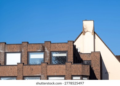 Building facade showcasing brickwork, windows, and an angled roofline against a clear blue sky