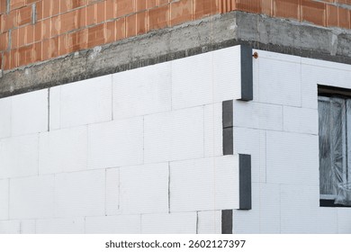 building facade under construction is covered with insulation panels. The thermal insulation is installed over a brick and concrete structure