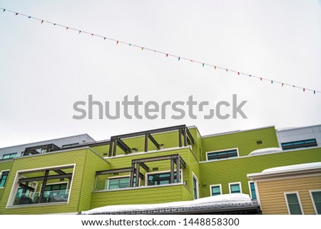 Building with green horizontal siding and balconies with glass railings