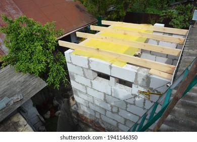 Building Home Addition From Autoclaved Aerated Concrete Blocks. Installing Wooden Ceiling Joists  And Vapor Barrier Over Brick Walls Of The House. 