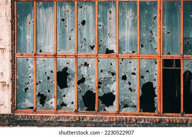 Building in industrial zone with windows broken from stones, bullets and shards. The concept of military conflict, ghettos and social theory of broken glass