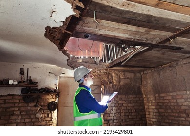 Building inspector. Man in a hard hat and a yellow reflective vest examines damaged structures and inspects the building. Damage assessment. Preparing for the repair or construction of a building