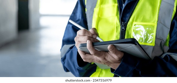 Building inspector man using digital tablet checking safety and security system in the building. Asian male worker in reflective vest working for building maintenance inspection - Powered by Shutterstock