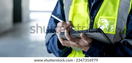 Building inspector man using digital tablet checking safety and security system in the building. Asian male worker in reflective vest working for building maintenance inspection