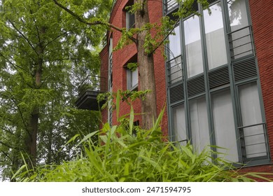 A building made of red bricks, surrounded by lush, lively vegetation