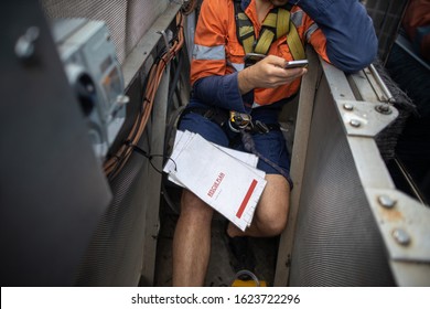 Building Maintenance Worker Is Using Cellphone Calling Site Emergency Services When Building Maintenance Unit Is Broken Down With Rescue Plan On His Leks At High Rise Building Sydney CBD Australia 