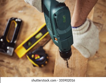 Building master with drilling machine. Professional carpenter working with wood and building tools in house.  
