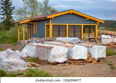 Building Materials On The Background Of A Country House Built. Sale Of Construction Materials. Delivery To The Construction Site. Construction Of Country Houses. Dacha. Outdoor Recreation.