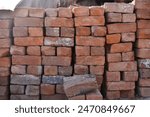 Building materials are on floor, stack red bricks. Production high-quality ceramic brick matte, reddish, porous fracture. Brick used for laying foundation. Purchase building material at hardware store