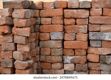 Building materials are on floor, stack red bricks. Production high-quality ceramic brick matte, reddish, porous fracture. Brick used for laying foundation. Purchase building material at hardware store