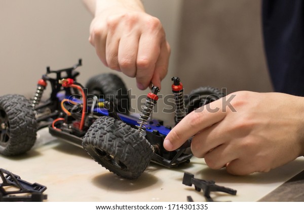 Building model cars. Radio control car assembly\
scene, RC car assembly on wooden work desk and tools. Building\
model cars. Radio control car assembly scene, RC car assembly on\
work desk and tools.