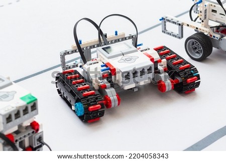 Building model RC robots concept. Caterpillar model of radio-controlled self-propelled vehicle.Radio control robot assembly on white desk. Professional toy RC models of robots. Natural lighting.