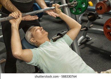 Building up muscles. Cropped shot of a senior man doing bench press exercise at the gym professional fitness trainer helping his elderly client working out professionalism support motivation sport - Powered by Shutterstock