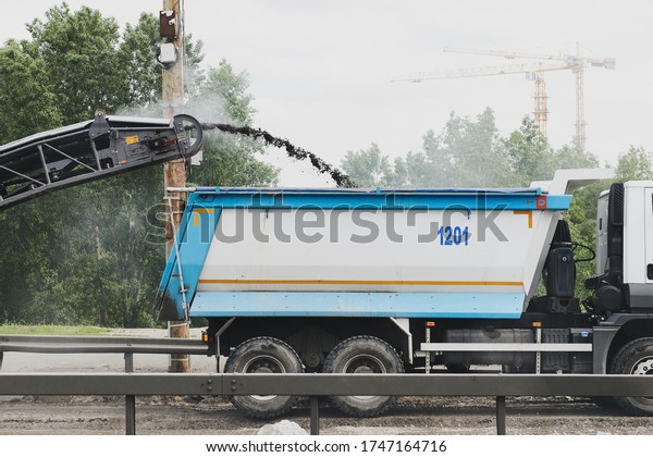 Building a new road. Road milling machine\
removing the old road. Construction machinery during work. Truck\
and machine.