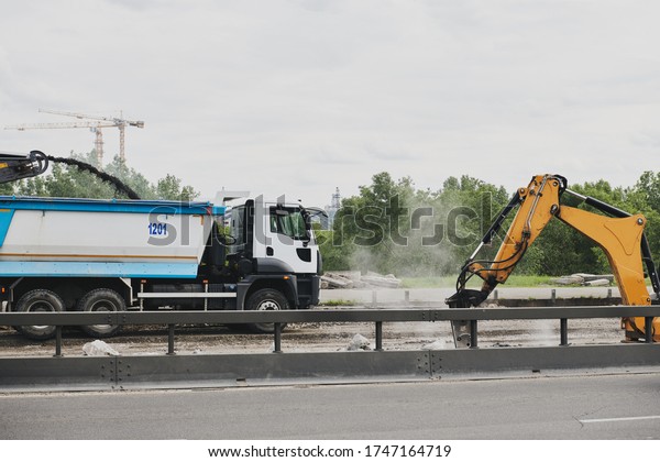 Building a new road. Road milling machine\
removing the old road. Construction machinery during work. Truck\
and excavator.