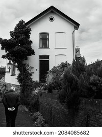 A Building Next To An Old City Wall With An Older Man Walking Past. 