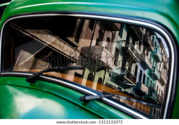 Building reflected in\
classic Cuban car