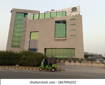 The building of the regional head office of MCB bank in the city with a green colored rickshaw passing next to it -  Lahore Pakistan - Dec 2020