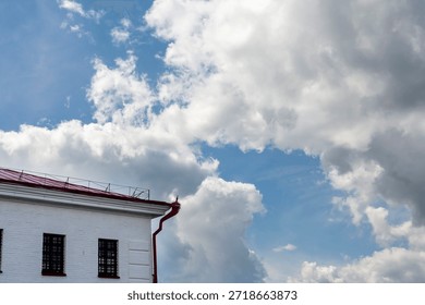 Building rooftops and dramatic cumulus clouds in the morning sky. A close-up of beautiful multicolored cumulus clouds against a blue sky.
