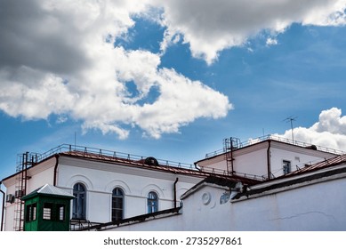 Building rooftops and dramatic cumulus clouds in the morning sky. A close-up of beautiful multicolored cumulus clouds against a blue sky.