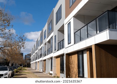 Building of a row of brand new 3-story residential townhouses in a suburb of Australia. Concept of the housing market, real estate development, property investment and home ownership.