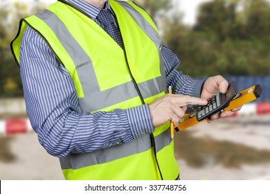 Building Surveyor In Hi Vis Vest With Calculator And Spirit Level