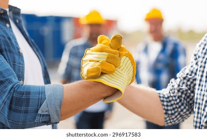 building, teamwork, partnership, gesture and people concept - close up of builders hands in gloves greeting each other with handshake on construction site