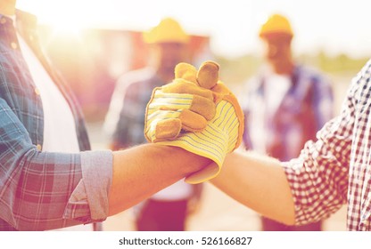 building  teamwork  partnership  gesture   people concept    close up builders hands in gloves greeting each other and handshake construction site