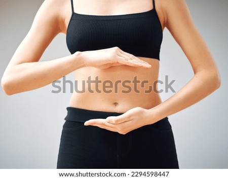Building that mind gut connection. Shot of a woman forming a circle with her hands in front of her belly.