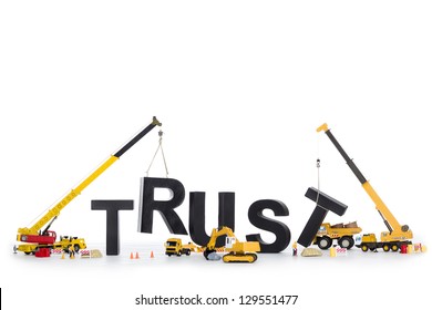 Building up trust concept: Black alphabetic letters forming the word trust being set up by group of construction machines, isolated on white background.
