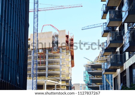 Building under construction and cranes under a cloudy sky