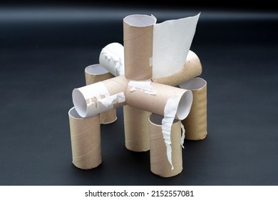 Building In View Of A Fort Made Of Empty Toilet Paper Rolls. House Made Of Cardboard Cylinders On A Dark Background. Background On The Theme Of Ecology And Recycling Of Materials.