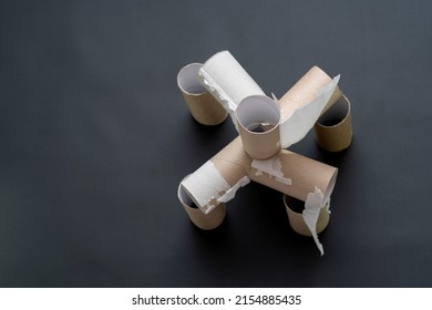 Building In View Of A Fort Made Of Empty Toilet Paper Rolls. House Made Of Cardboard Cylinders On A Dark Background. The Concept Is A Crisis, An Unreliable Economy And A Lack Of Basic Amenities