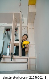 Building a wardrobe. Man using Framing Nailer to attach wooden plywoods.