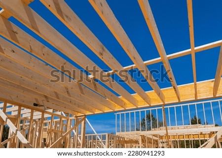 Building wooden house begins with framing beams which support layout of joists.