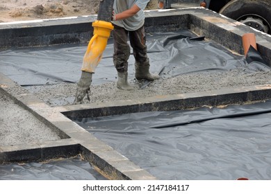 A Building Worker Pouring A Concrete Slab Foundation Using A Hose Of A Concrete Pump Truck