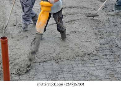 A Building Worker Pouring A Concrete Slab Foundation Using A Hose Of A Concrete Pump Truck And A Builder Levelling And Spreading Concrete With A Rake