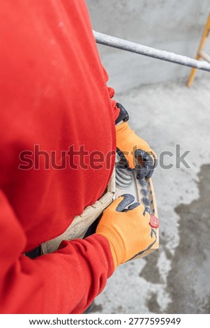 A building worker using a remote control during building construction, wearing safety gloves