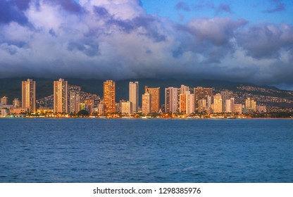 Buildings of downtown Honolulu light up during sunset.