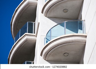 Building's facade. Semicircular balconies. Glass railings. Glass fencing.
