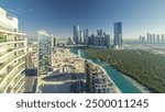 Buildings on Al Reem island in Abu Dhabi timelapse panorama from above. Aerial cityscape of Al Reem Island at evening, showing the reflection of buildings in the water and long shadows.