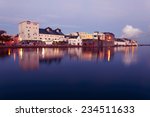 Buildings on the bank of the river during High tide in the city in dusk. Claddach, Galway, Ireland.
